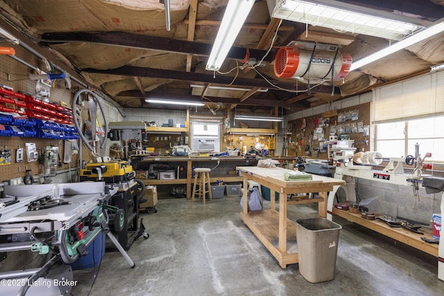 miscellaneous room featuring a workshop area and unfinished concrete floors