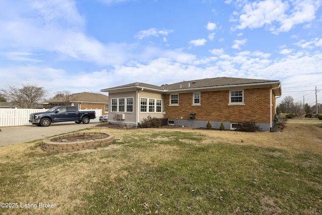 back of property featuring brick siding, roof with shingles, a yard, and fence