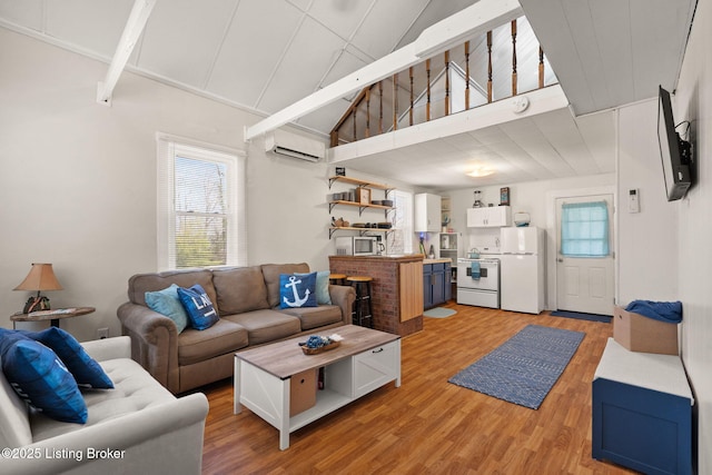 living room with high vaulted ceiling, light wood-style floors, and a wall unit AC