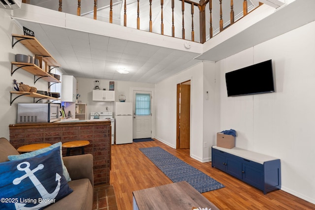 living room featuring baseboards, light wood-style floors, and a wall unit AC