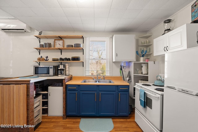 kitchen featuring white appliances, open shelves, blue cabinetry, a sink, and an AC wall unit