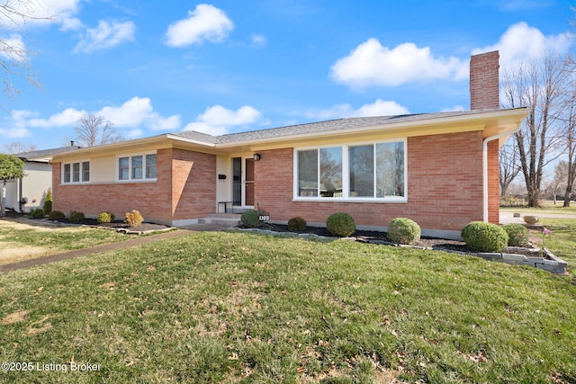 ranch-style house with brick siding, a front yard, and a chimney