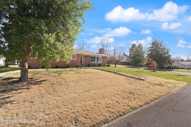 ranch-style house featuring a front yard, brick siding, and a chimney