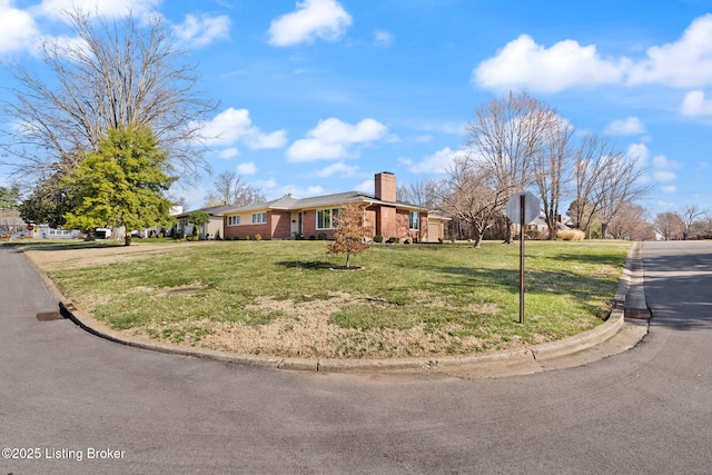 ranch-style house featuring a front lawn, brick siding, and a chimney