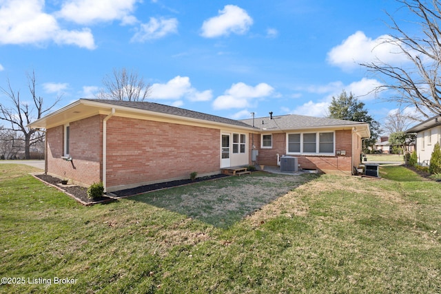 rear view of house featuring brick siding, central air condition unit, a lawn, and entry steps