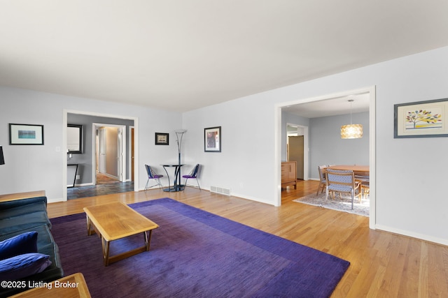 living area with visible vents, baseboards, and wood finished floors