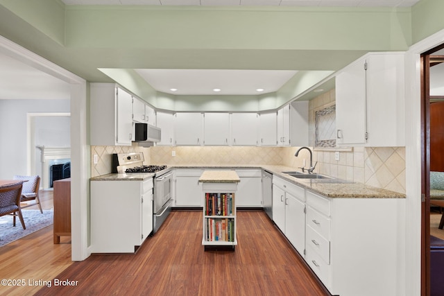 kitchen with dark wood-style floors, a sink, stainless steel appliances, white cabinetry, and tasteful backsplash