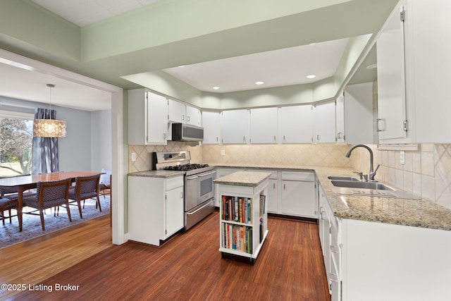 kitchen with a sink, backsplash, dark wood-style floors, white cabinetry, and stainless steel appliances