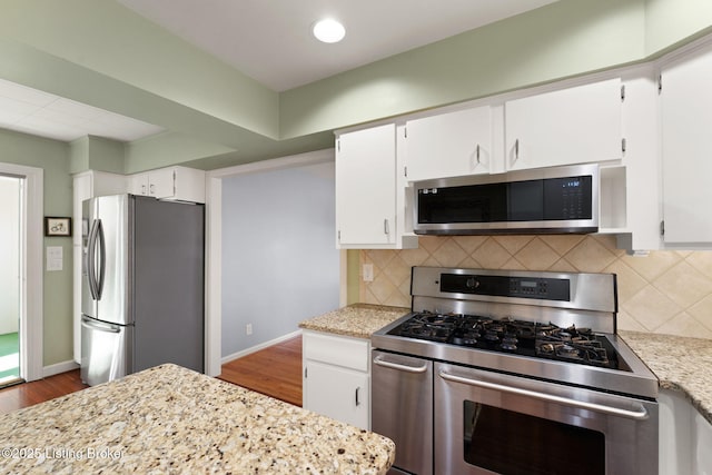 kitchen with stainless steel appliances, backsplash, white cabinets, and dark wood finished floors