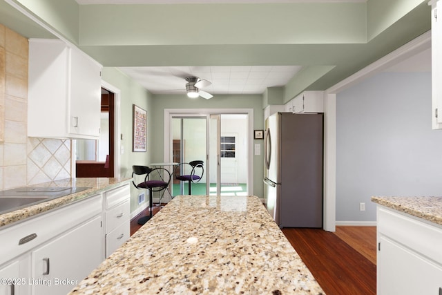 kitchen with ceiling fan, dark wood finished floors, decorative backsplash, freestanding refrigerator, and white cabinetry