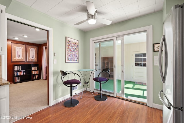 interior space with a ceiling fan, wood finished floors, and baseboards