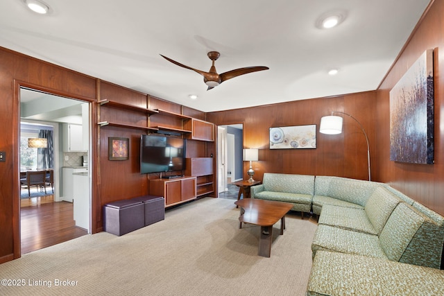 carpeted living room with wooden walls, recessed lighting, and ceiling fan