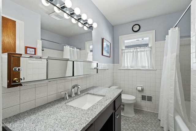 bathroom featuring vanity, visible vents, tile walls, toilet, and tile patterned floors