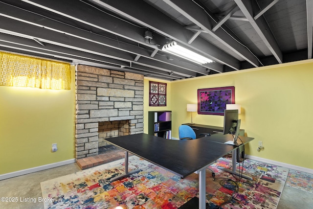 office area featuring a fireplace, baseboards, and concrete floors