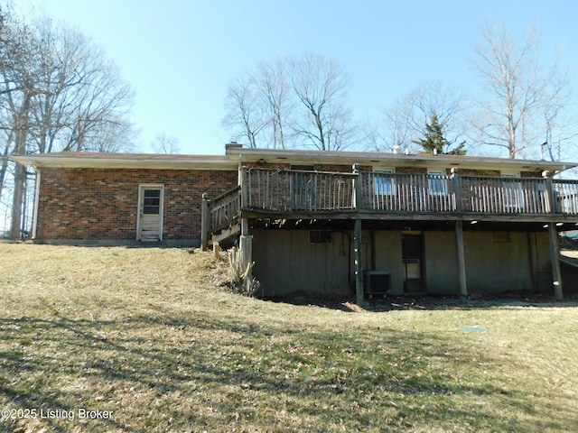 rear view of property with a lawn, central AC unit, brick siding, and a wooden deck