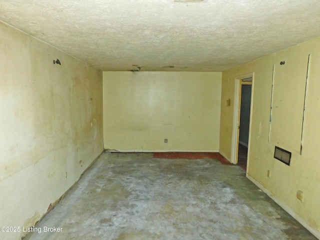 spare room with a textured ceiling and unfinished concrete flooring