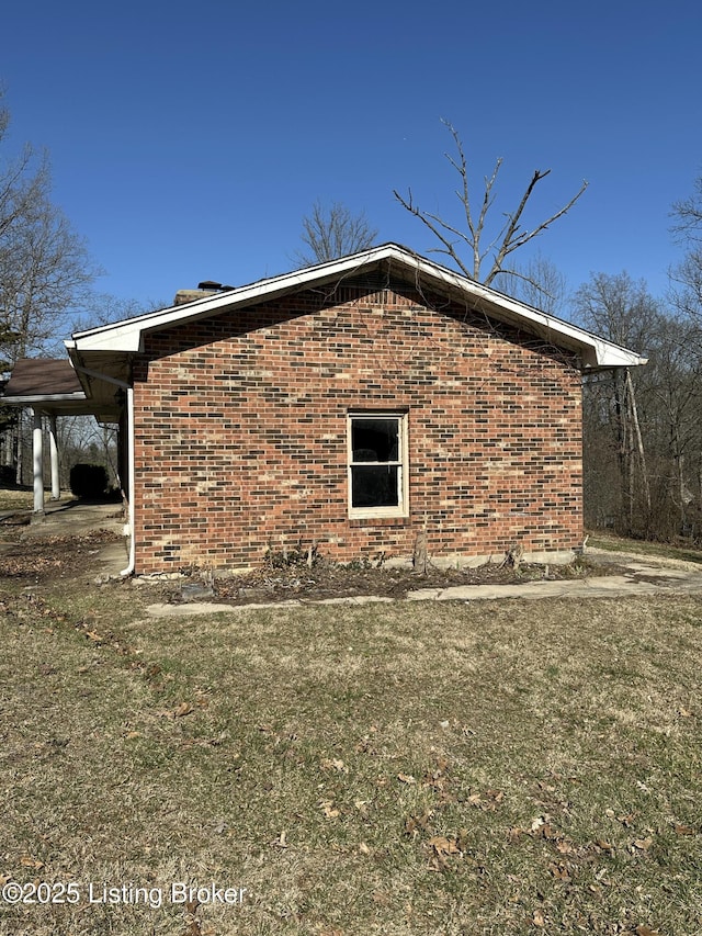 view of side of home with brick siding and a lawn