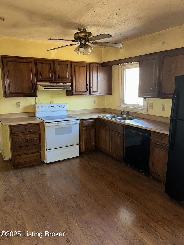 kitchen with dark wood finished floors, a sink, black appliances, light countertops, and under cabinet range hood