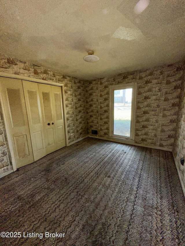 unfurnished bedroom featuring carpet flooring, a closet, and a textured ceiling