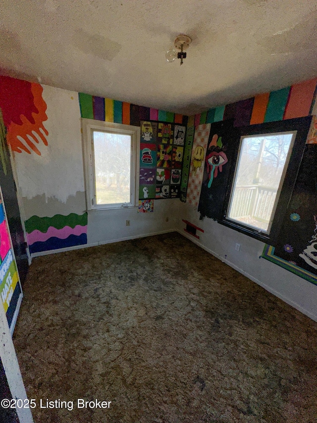 spare room featuring a textured ceiling, baseboards, and carpet floors