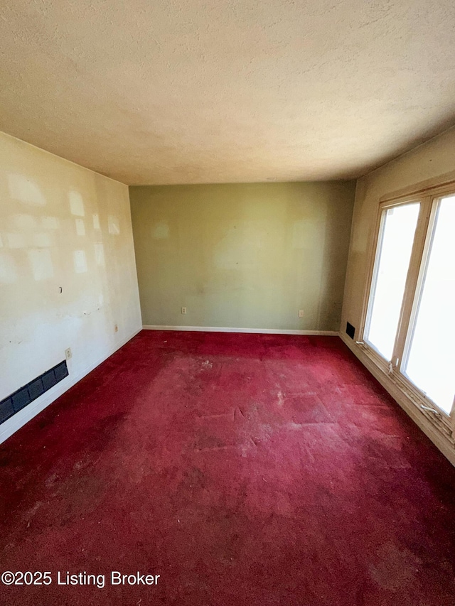 carpeted empty room with baseboards and a textured ceiling