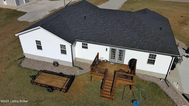 rear view of property with a yard, a deck, french doors, and roof with shingles