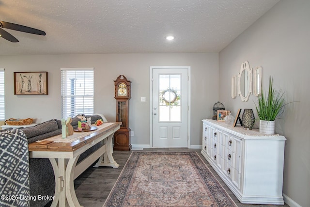 foyer with ceiling fan, baseboards, a textured ceiling, and wood finished floors