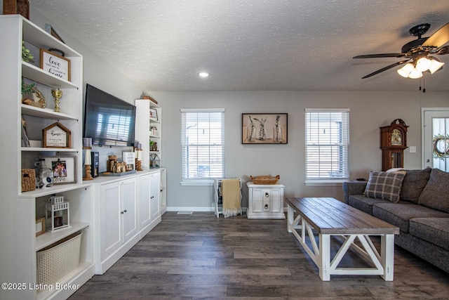 living area featuring a wealth of natural light, a textured ceiling, dark wood-type flooring, and a ceiling fan