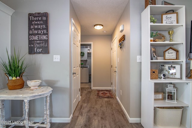 hall with wood finished floors, baseboards, and a textured ceiling