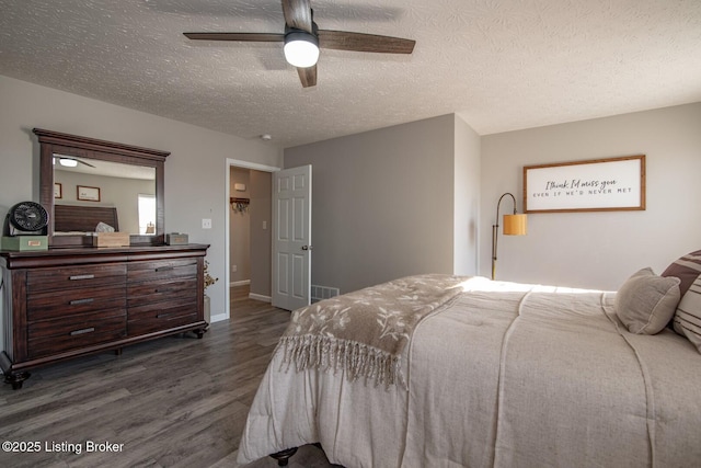 bedroom featuring visible vents, a textured ceiling, dark wood-style floors, baseboards, and ceiling fan