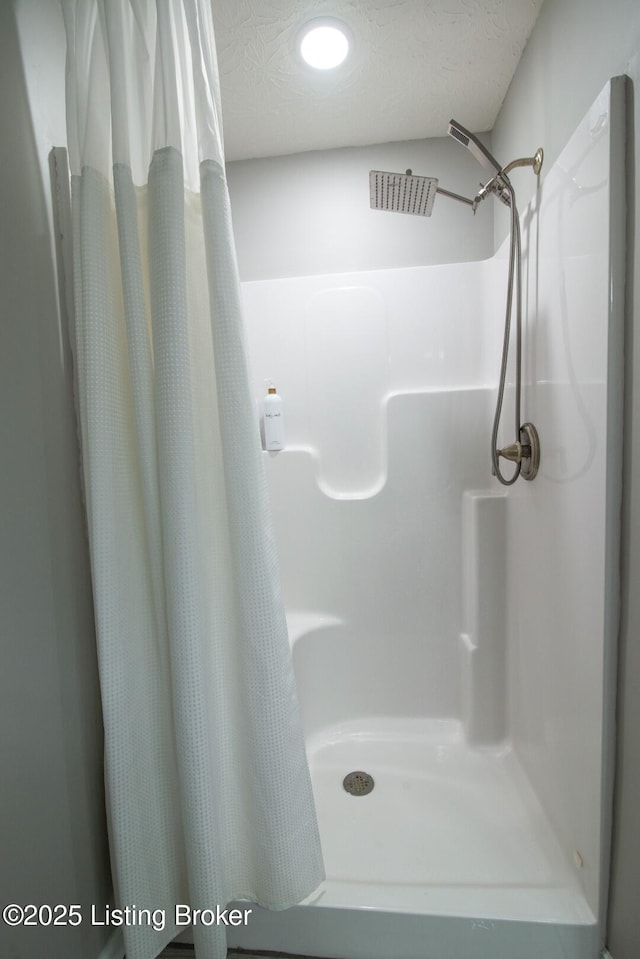 bathroom with curtained shower and a textured ceiling