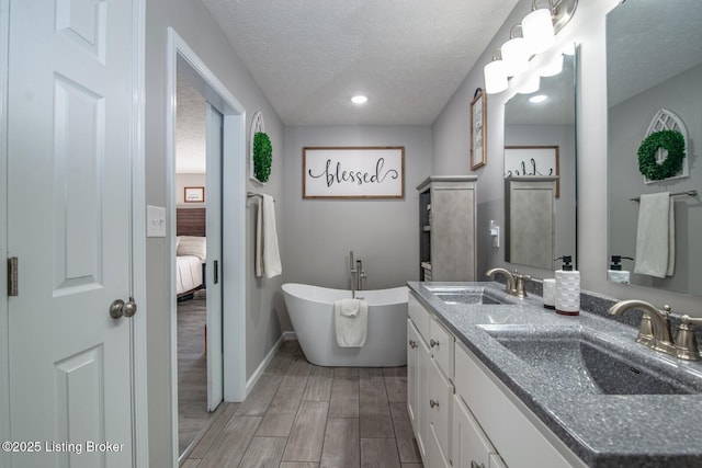 full bath with a sink, a freestanding tub, a textured ceiling, and wood tiled floor