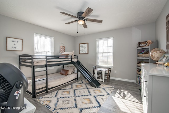 bedroom with baseboards, multiple windows, wood finished floors, and a ceiling fan