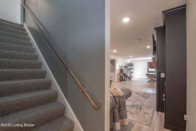 stairs with visible vents, recessed lighting, and wood finished floors