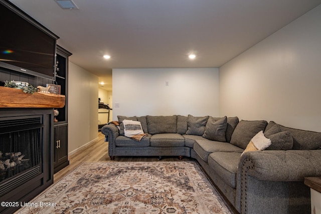 living room featuring light wood-style flooring, recessed lighting, a fireplace, and visible vents