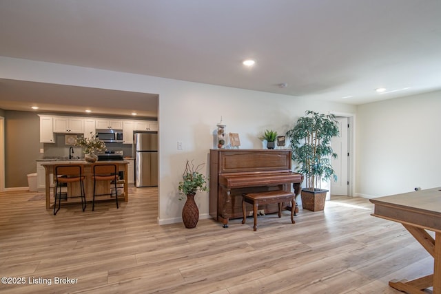 living area with recessed lighting, baseboards, and light wood finished floors