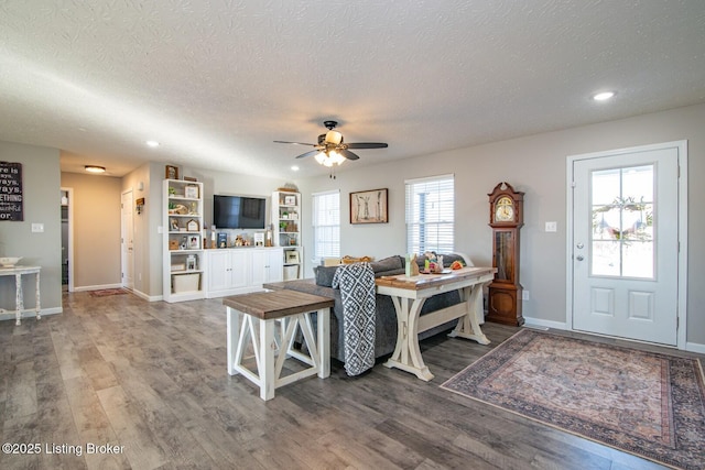 living area with baseboards, a textured ceiling, wood finished floors, and a ceiling fan