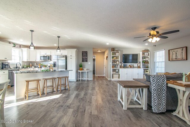 kitchen featuring white cabinets, dark wood-style floors, appliances with stainless steel finishes, and a center island