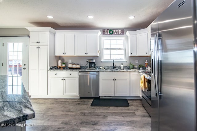 kitchen featuring a healthy amount of sunlight, appliances with stainless steel finishes, stone countertops, and a sink