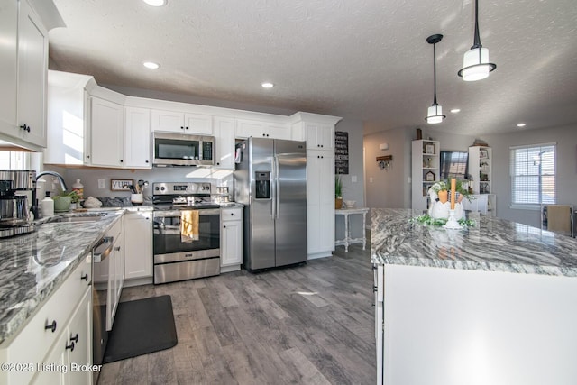 kitchen featuring wood finished floors, white cabinetry, stainless steel appliances, and a sink