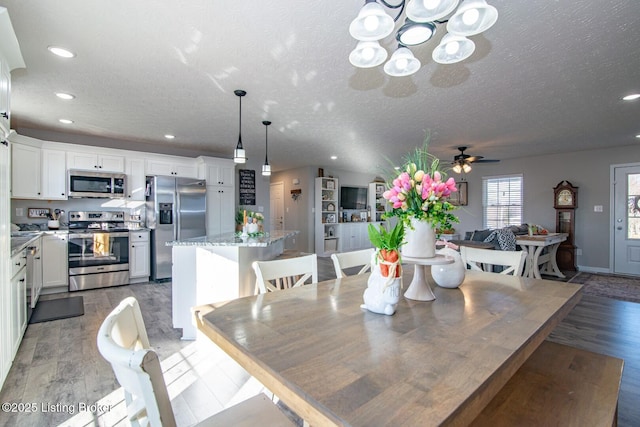 dining room with ceiling fan with notable chandelier, recessed lighting, a textured ceiling, and light wood-type flooring