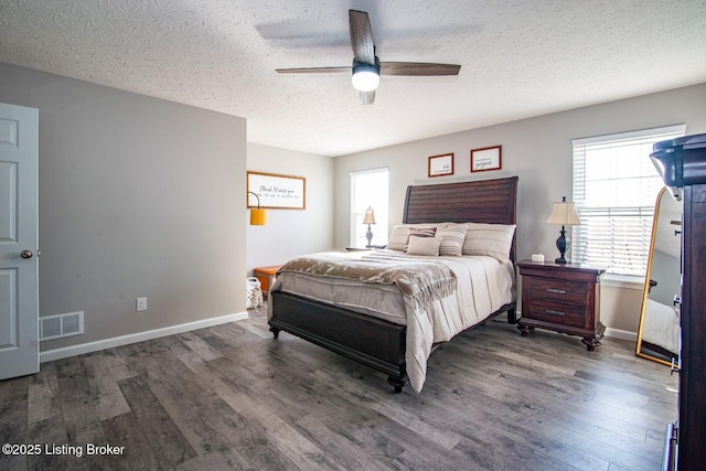 bedroom with a ceiling fan, wood finished floors, visible vents, and baseboards