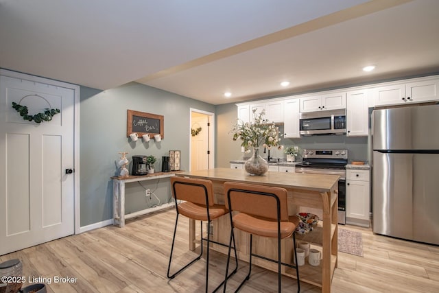 kitchen featuring light wood-type flooring, appliances with stainless steel finishes, and white cabinets