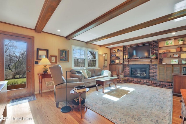 living area with built in shelves, baseboards, beamed ceiling, a fireplace, and wood finished floors