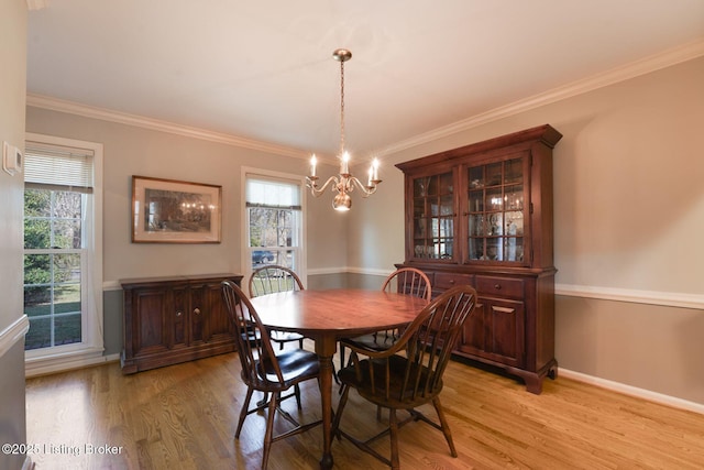 dining space featuring a chandelier, light wood-type flooring, baseboards, and ornamental molding