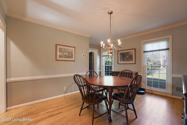 dining area with ornamental molding, light wood-style floors, visible vents, and a chandelier