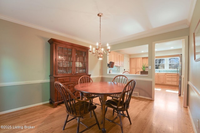 dining space featuring crown molding, a notable chandelier, baseboards, and light wood finished floors