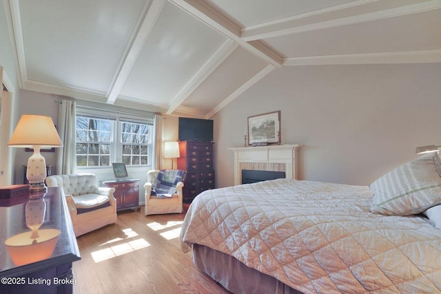 bedroom with a fireplace, vaulted ceiling with beams, and wood finished floors