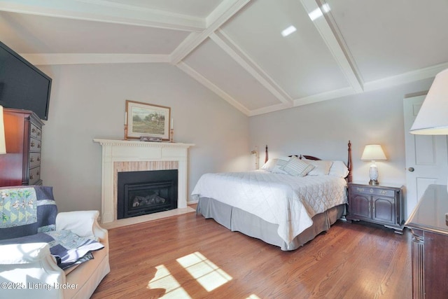 bedroom featuring a brick fireplace, wood finished floors, and vaulted ceiling with beams