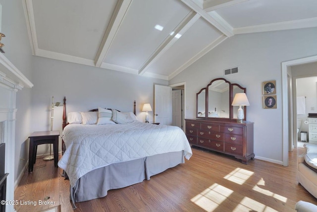 bedroom featuring visible vents, vaulted ceiling with beams, baseboards, and wood finished floors